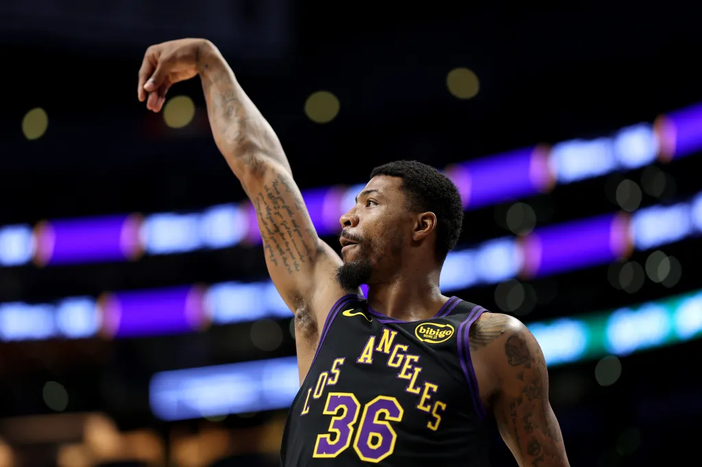 Marcus Smart in a Lakers jersey with his arm raised.
