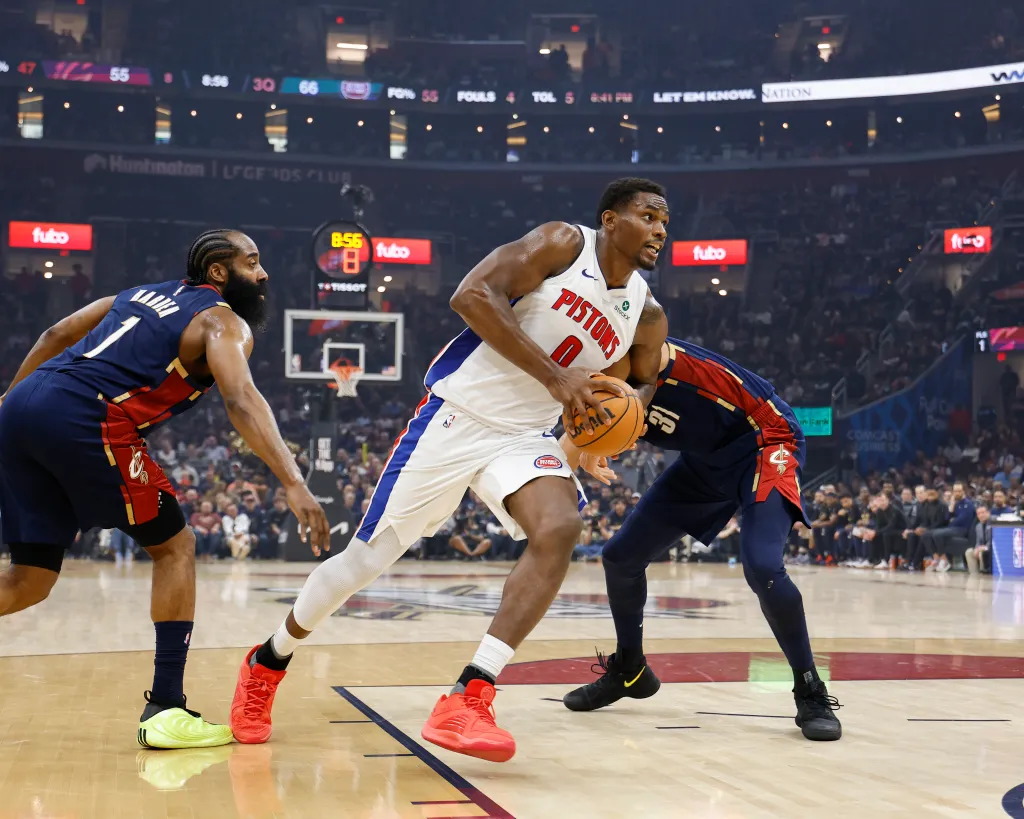 Jalen Duren of the Pistons dribbles the ball between two Cavaliers players during a game.