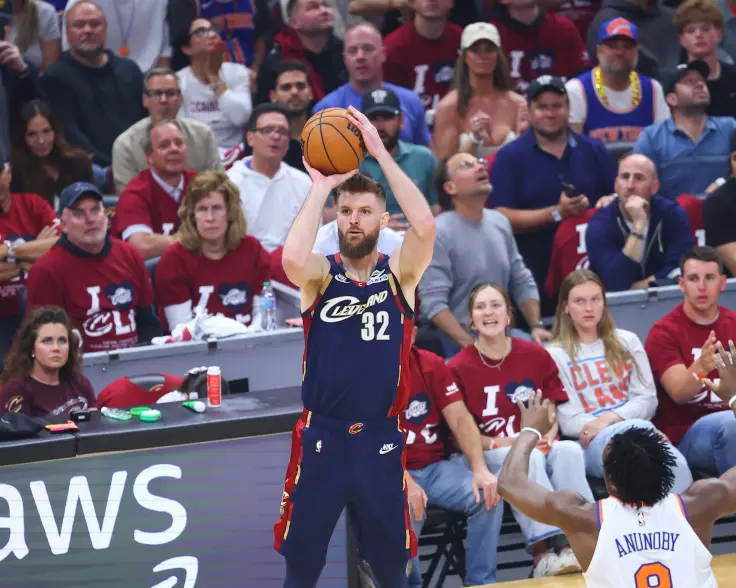 Dean Wade of the Cavaliers, wearing a blue jersey with "CLEVELAND 32" and red accents, shoots a basketball.