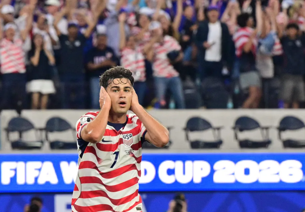 A male soccer player in a USA uniform with the number 7 covers his ears.