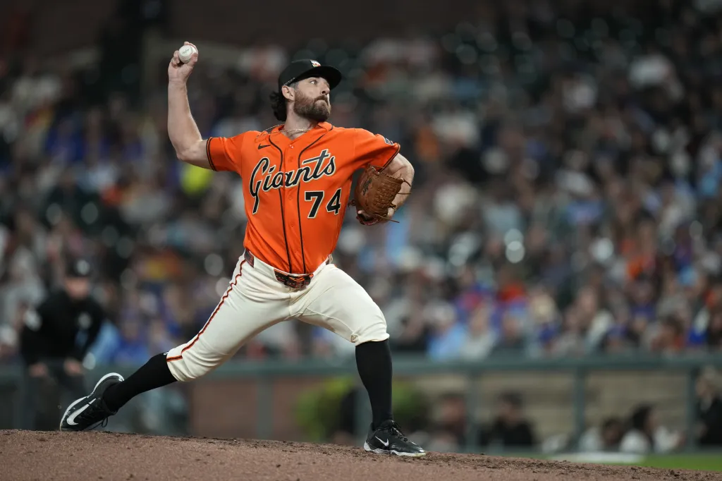 Giants pitcher Ryan Walker in an orange jersey with number 74, mid-pitch, looking up and to the right.