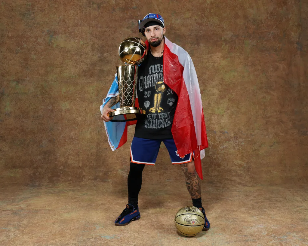 Jose Alvarado, wrapped in the Puerto Rican flag, celebrates with the 2026 NBA Championship. 