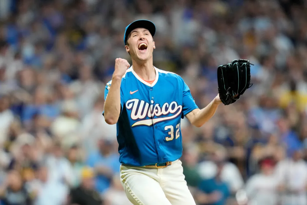 A Milwaukee Brewers player in a blue jersey with "Wisco" written on it celebrates after making a play.