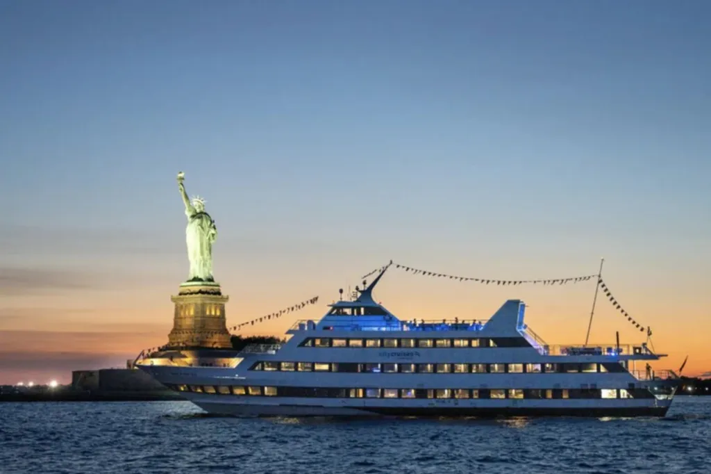 An image of the statue of Liberty and a boat on the water at night.