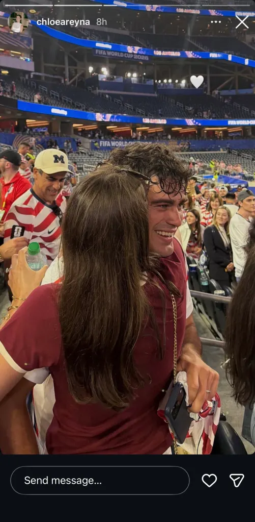 A woman with long brown hair, seen from behind, embraces a smiling man at a FIFA World Cup 2026 event in Los Angeles.