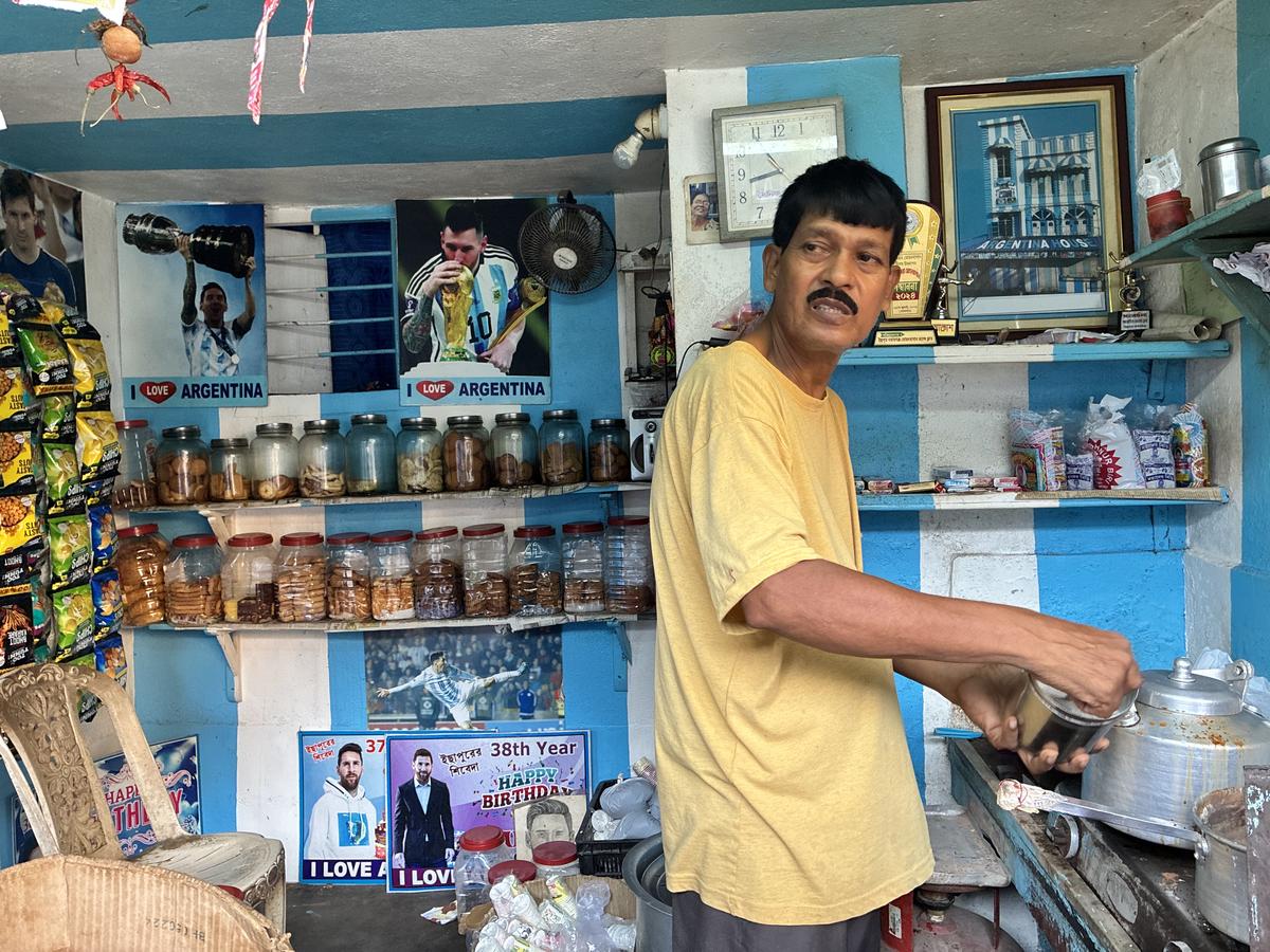 Shib Shankar Patra serves tea at his stall beneath a signed photograph of Lionel Messi featuring the tea seller’s Argentina themed home in Ichhapur.