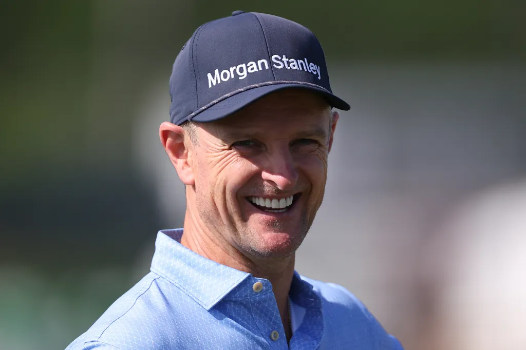 A smiling male golfer in a blue shirt and a navy "Morgan Stanley" cap during a practice round.