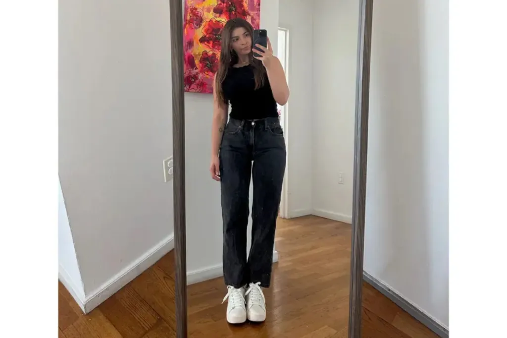 A woman taking a selfie while wearing jeans