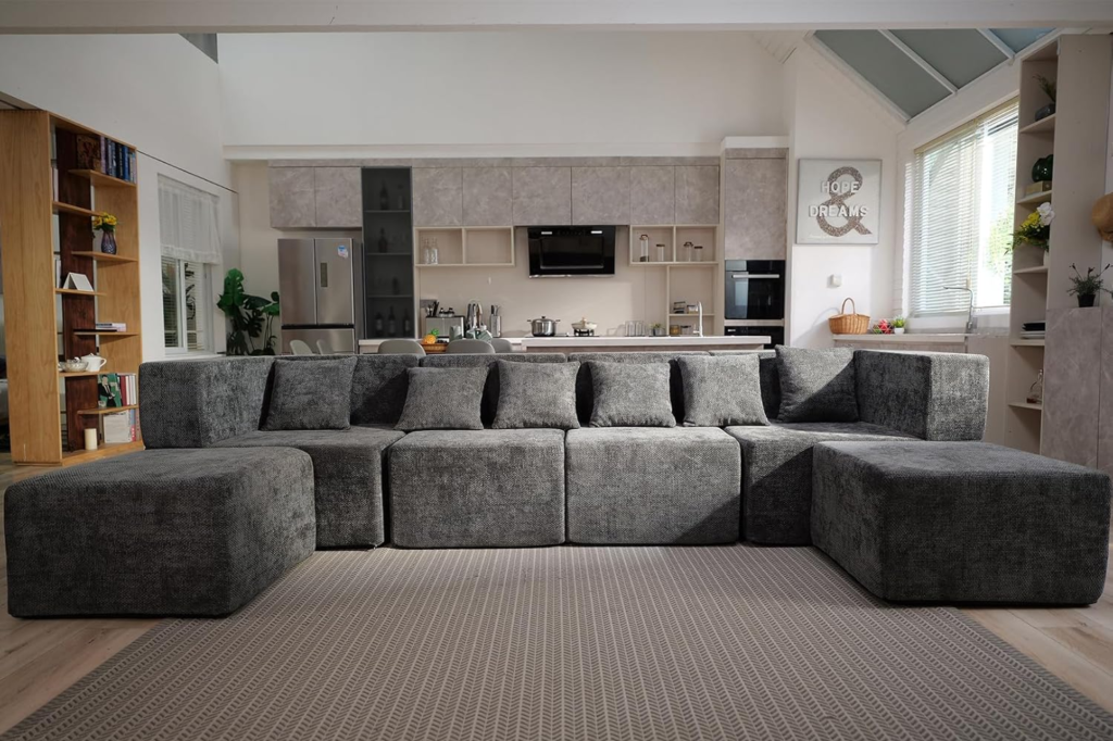 A large, gray modular sofa in a modern open-concept living room and kitchen.