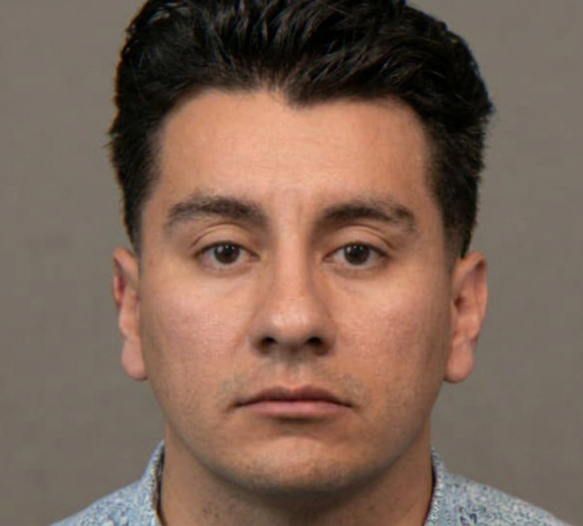 A man with dark hair and brown eyes looks directly at the camera.