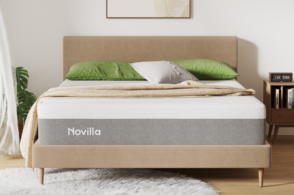 Novilla mattress on a bed frame with green and grey pillows.