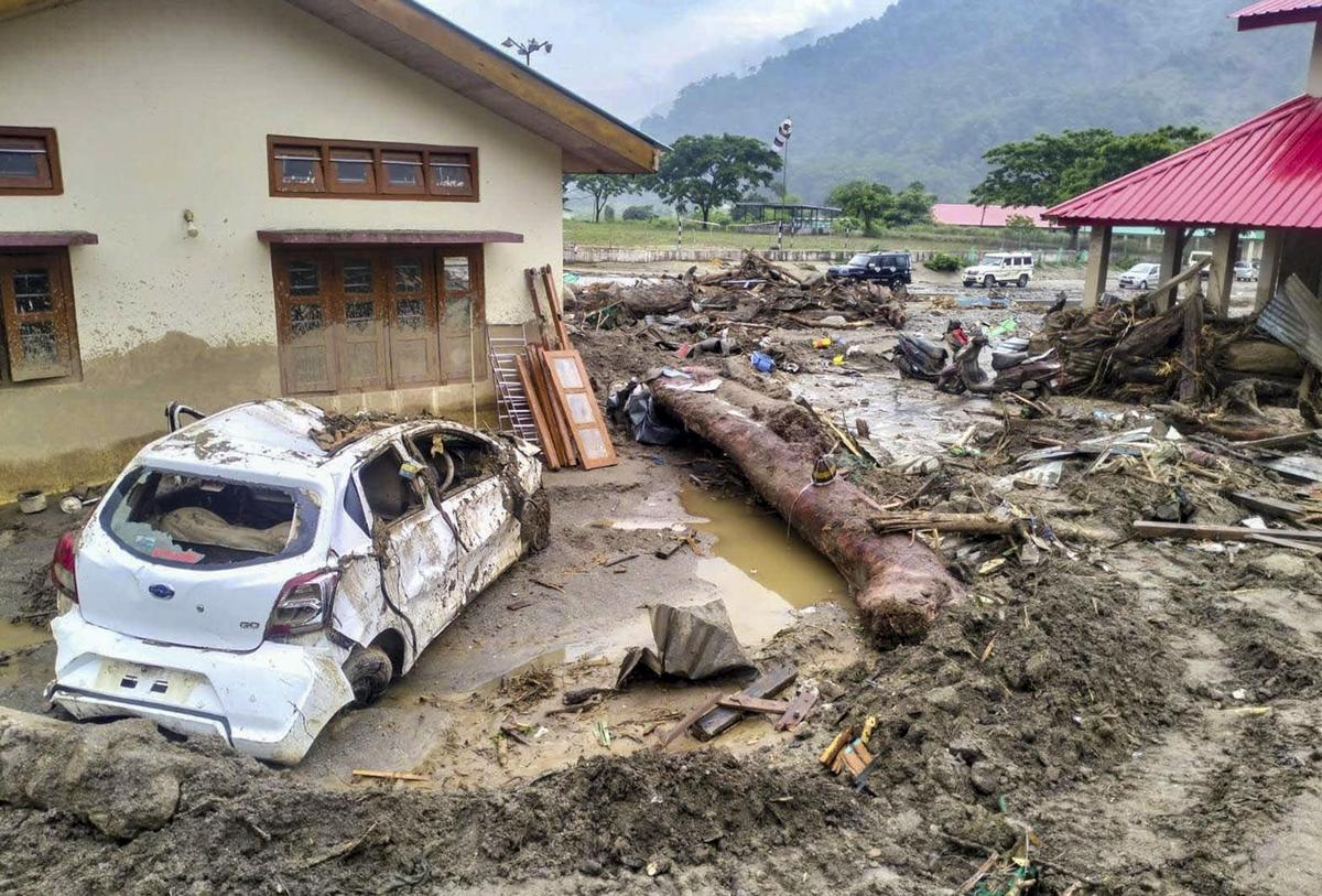 A damaged car and uprooted logs lie amid debris after a devastating flash flood struck the NEEPCO Colony, in Keyi Panyor district, Arunachal Pradesh, on Monday, June 29, 2026.