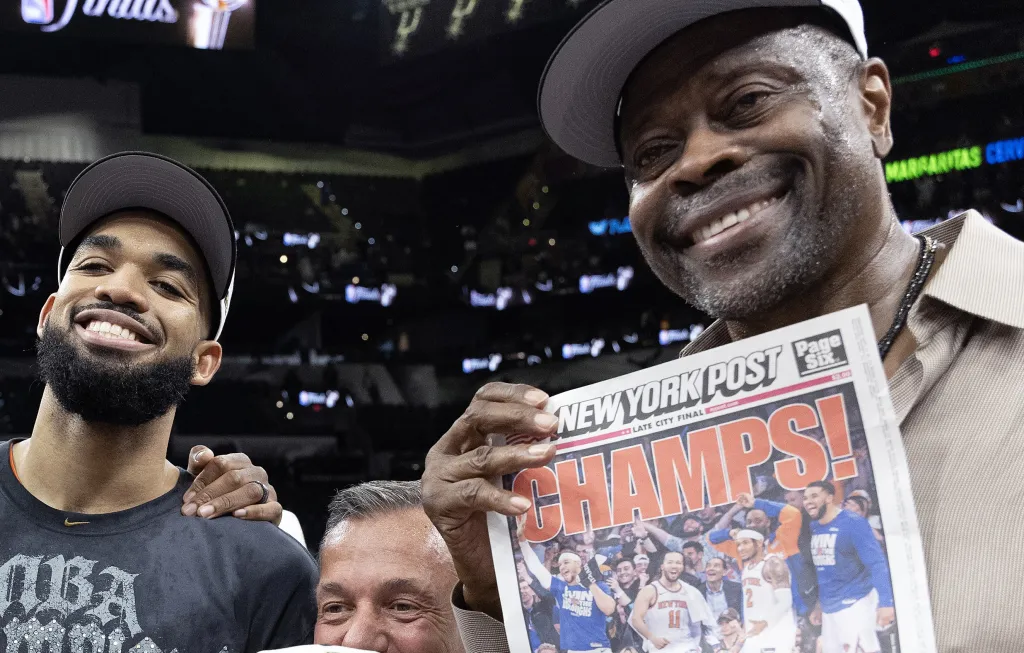 A smiling Patrick Ewing celebrates with Karl-Anthony Towns and a copy of the New York Post front page after the Knicks' 94-90 NBA title-clinching Game 5 win over the Spurs on July 13, 2026 in San Antonio.