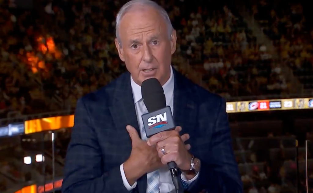 A man in a suit speaking into an SN Sportsnet microphone.