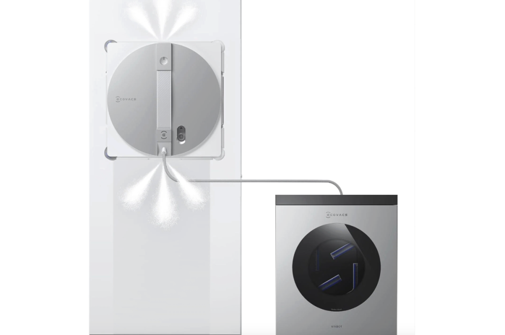 Illustration of a white WINBOT W3 OMNI window cleaning robot spraying water on a window, connected by a hose to a gray Winbot station.