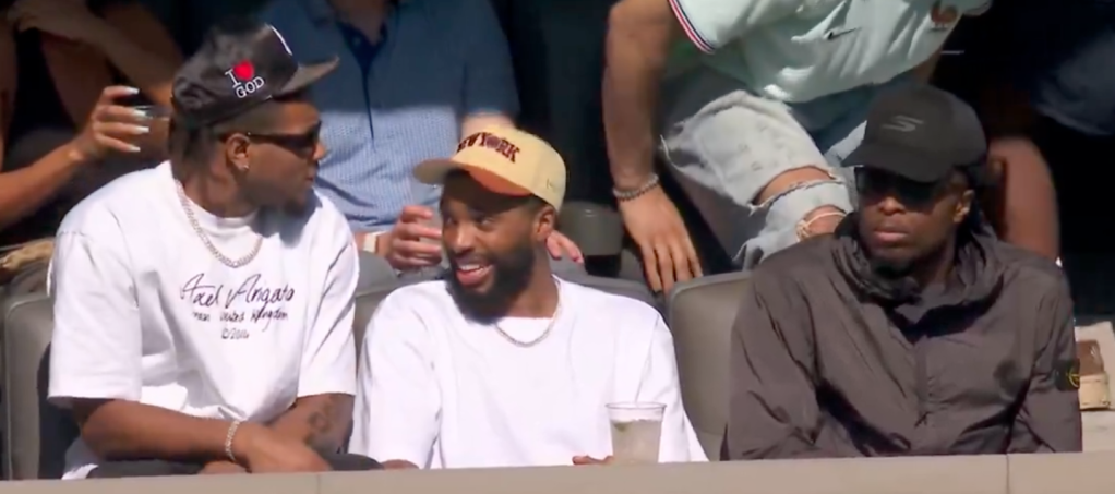 Three men watching a game from stadium seats.
