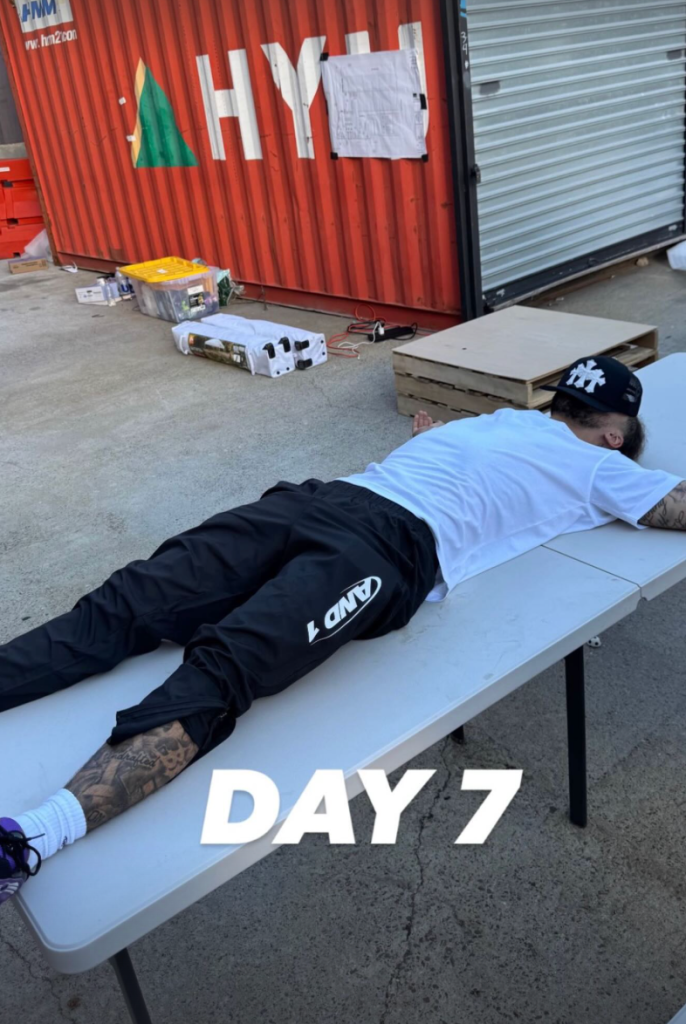 A person lies face down on a folding table, appearing exhausted, with "DAY 7" written over the image.