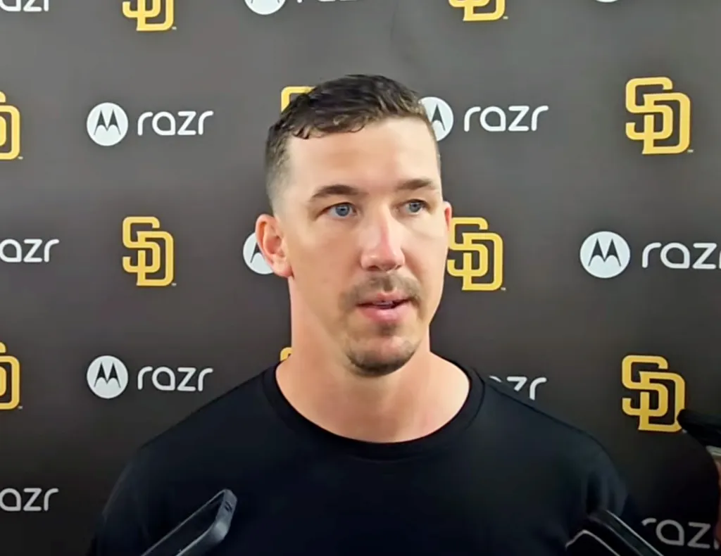 Man with blue eyes and a mustache talking in front of a black background with yellow Padres and white Motorola logos.