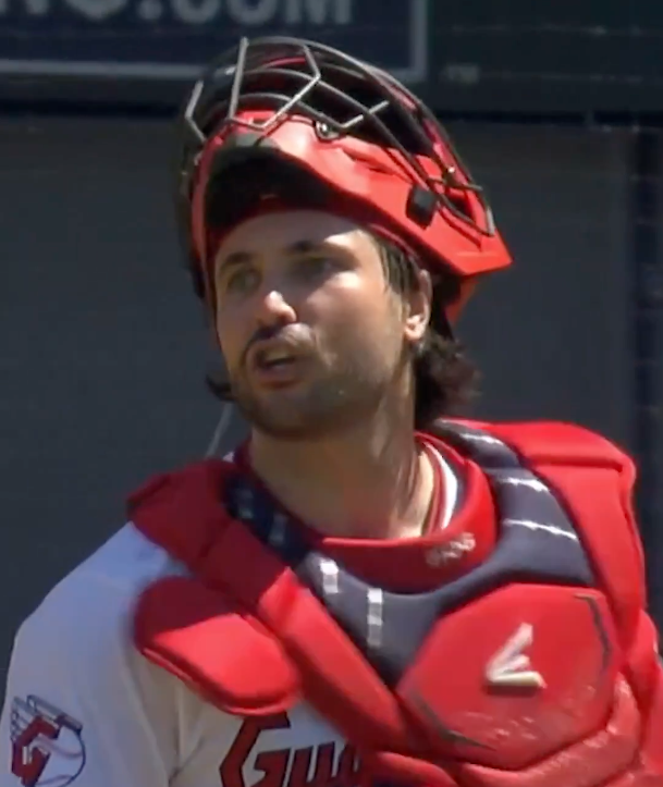 Baseball catcher in red and white uniform and red helmet.