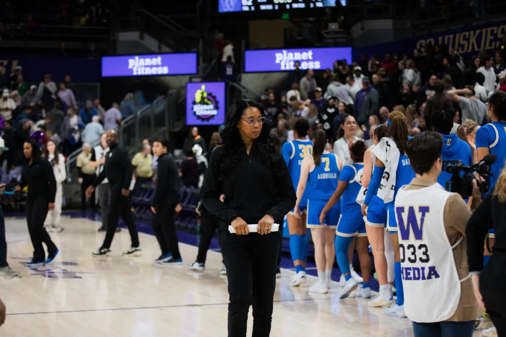 Shannon LeBeauf standing on a basketball court with a team of players.