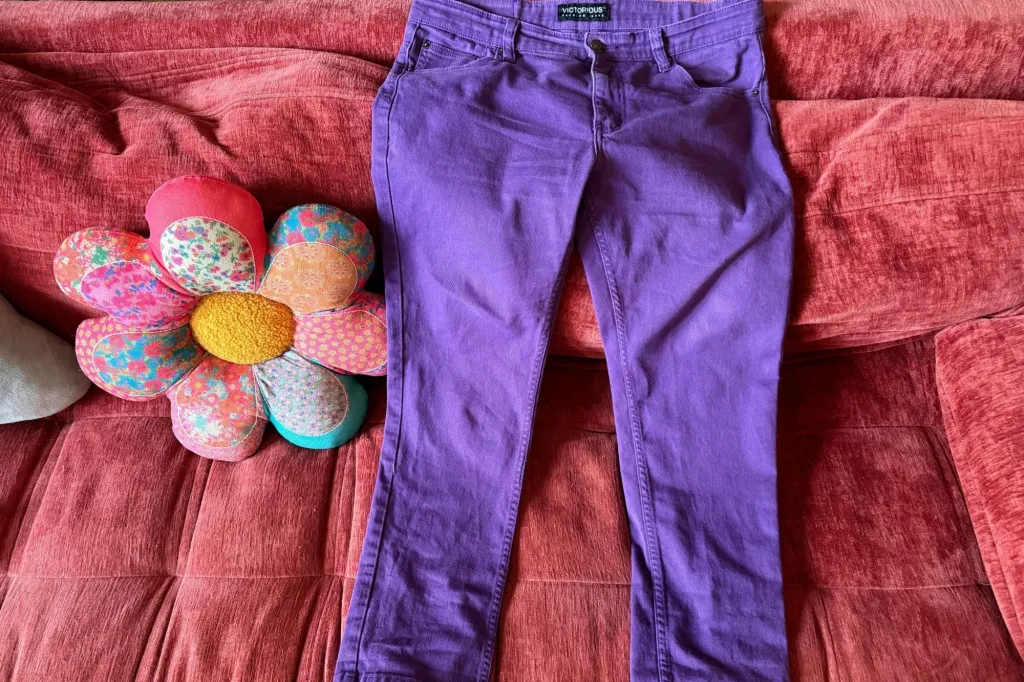 A pair of purple skinny jeans on a bed.