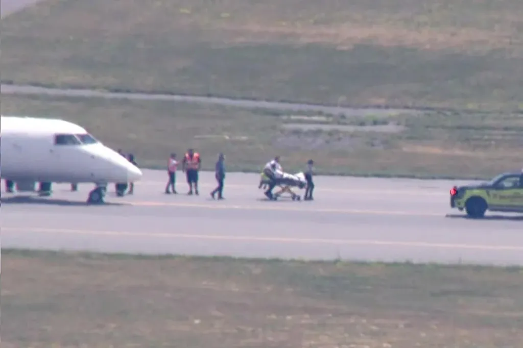 Medical personnel transporting a patient on a stretcher near an Air Canada plane.