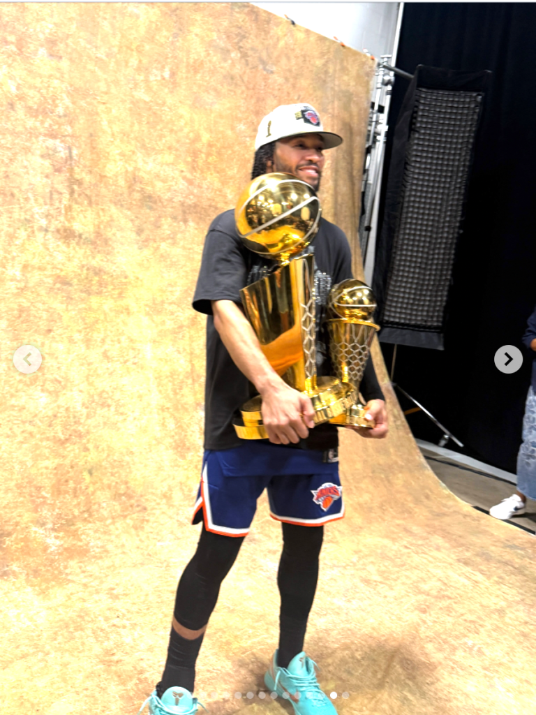 Ali Brunson holding two golden basketball trophies.