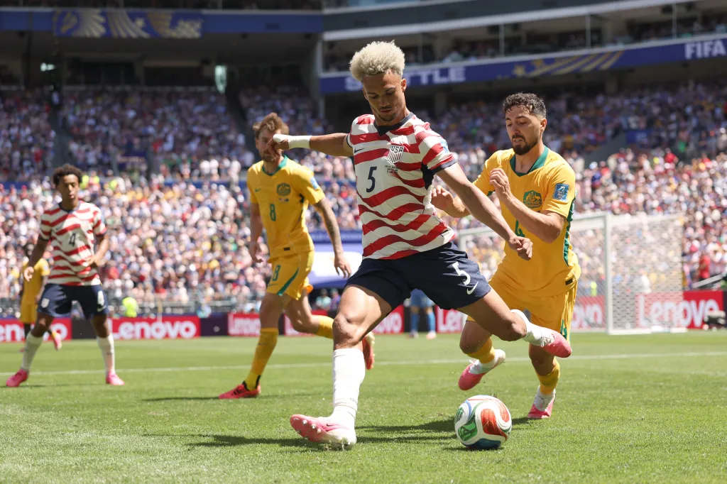 Antonee Robinson of the United States passes the ball under pressure from Jacob Italiano of Australia during a FIFA World Cup 2026 match.