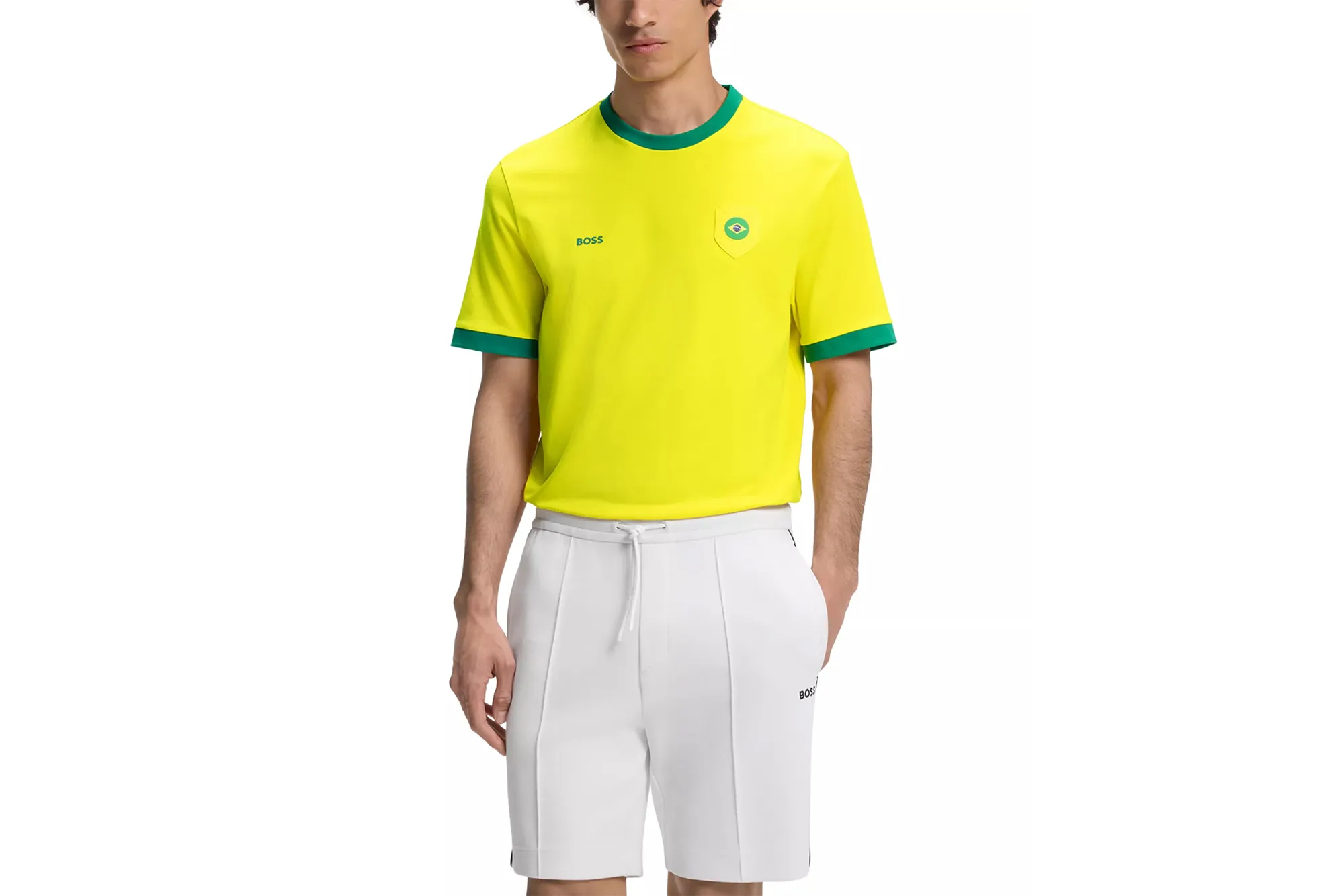 A man wearing a yellow Boss t-shirt with green trim and white shorts.