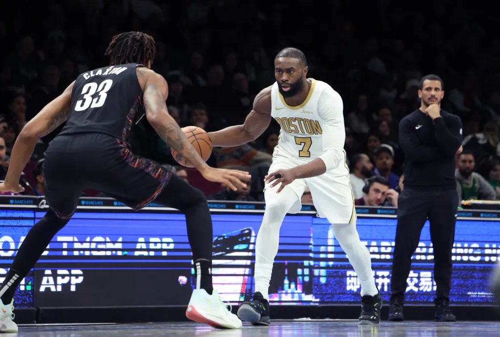 Boston Celtics guard Jaylen Brown dribbling the ball while guarded by Brooklyn Nets center Nic Claxton.
