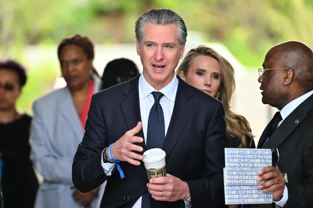 California Gov. Gavin Newsom speaks while holding a Starbucks coffee cup.