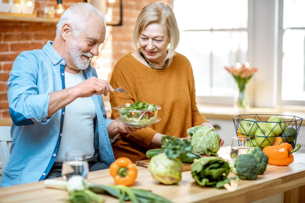 A cheerful senior couple preparing healthy food together in their kitchen.