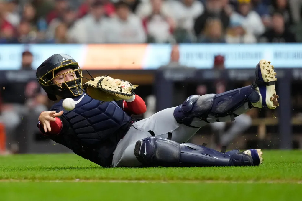 Cleveland Guardians' Patrick Bailey throws to first base from the ground during a baseball game.