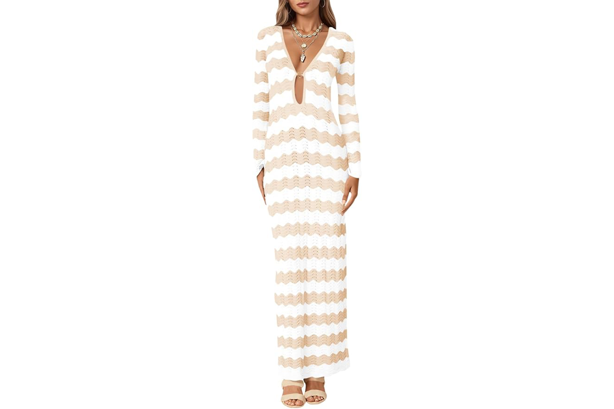 A woman wearing a white and beige chevron-patterned knit maxi dress with a deep V-neck and a gold layered necklace.