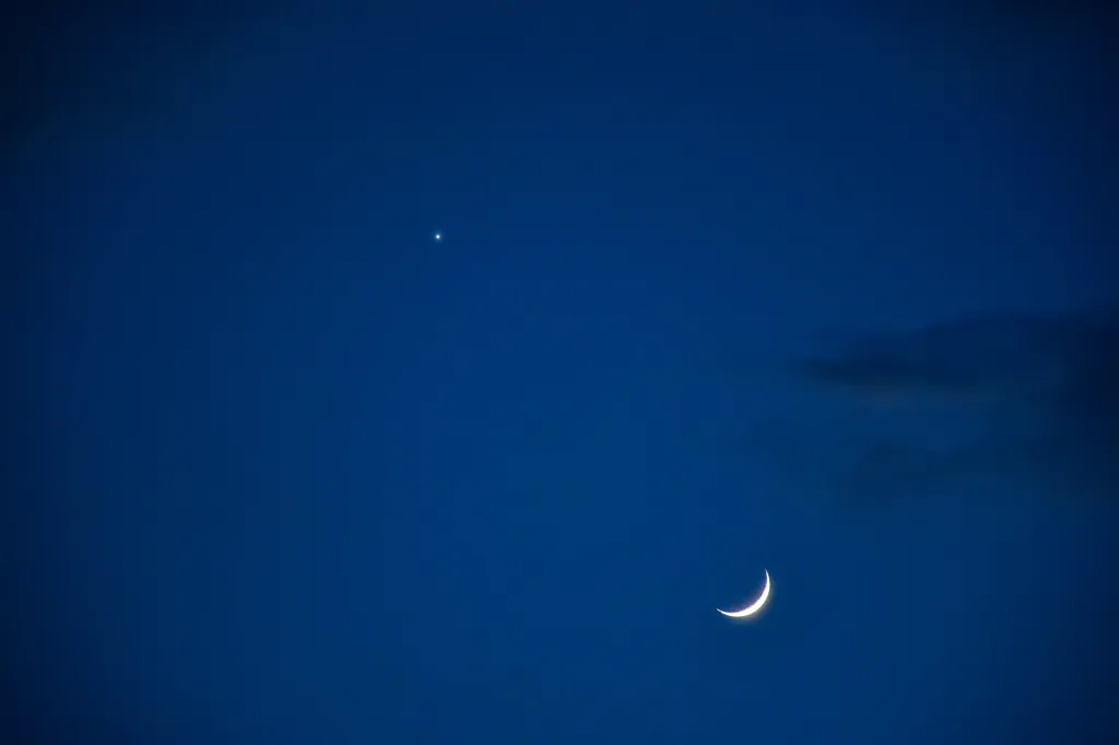 A crescent moon, Venus, and Jupiter in the evening sky during a planetary alignment.