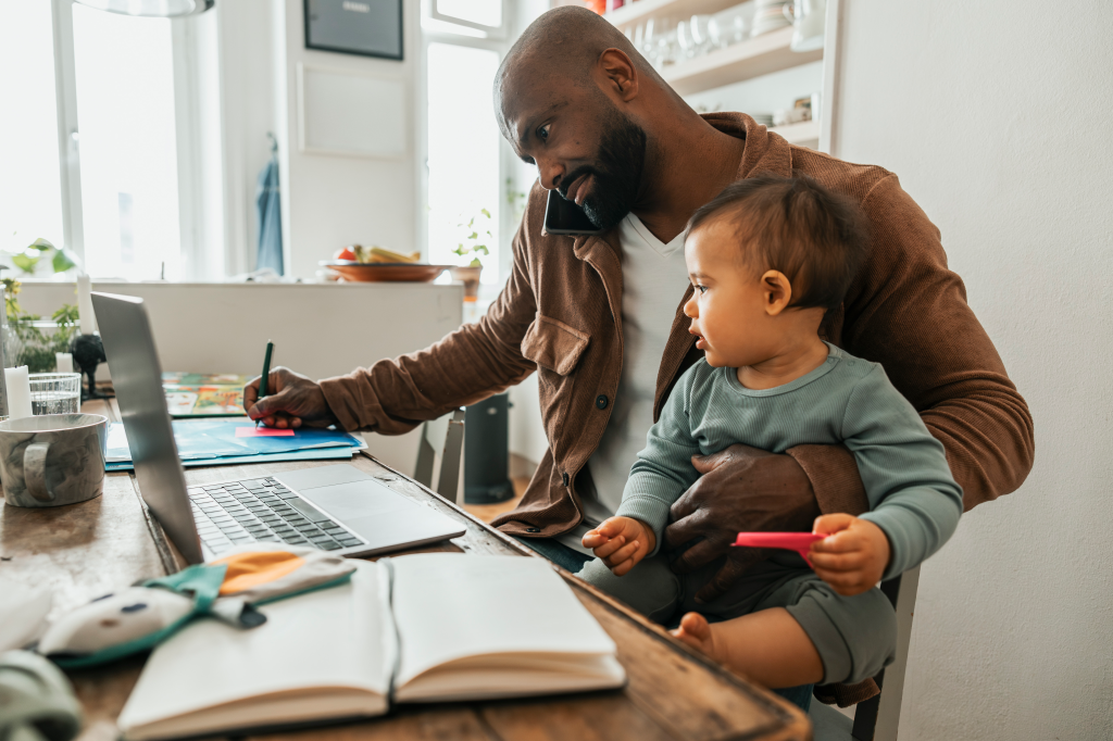 Father holding baby while working from home.