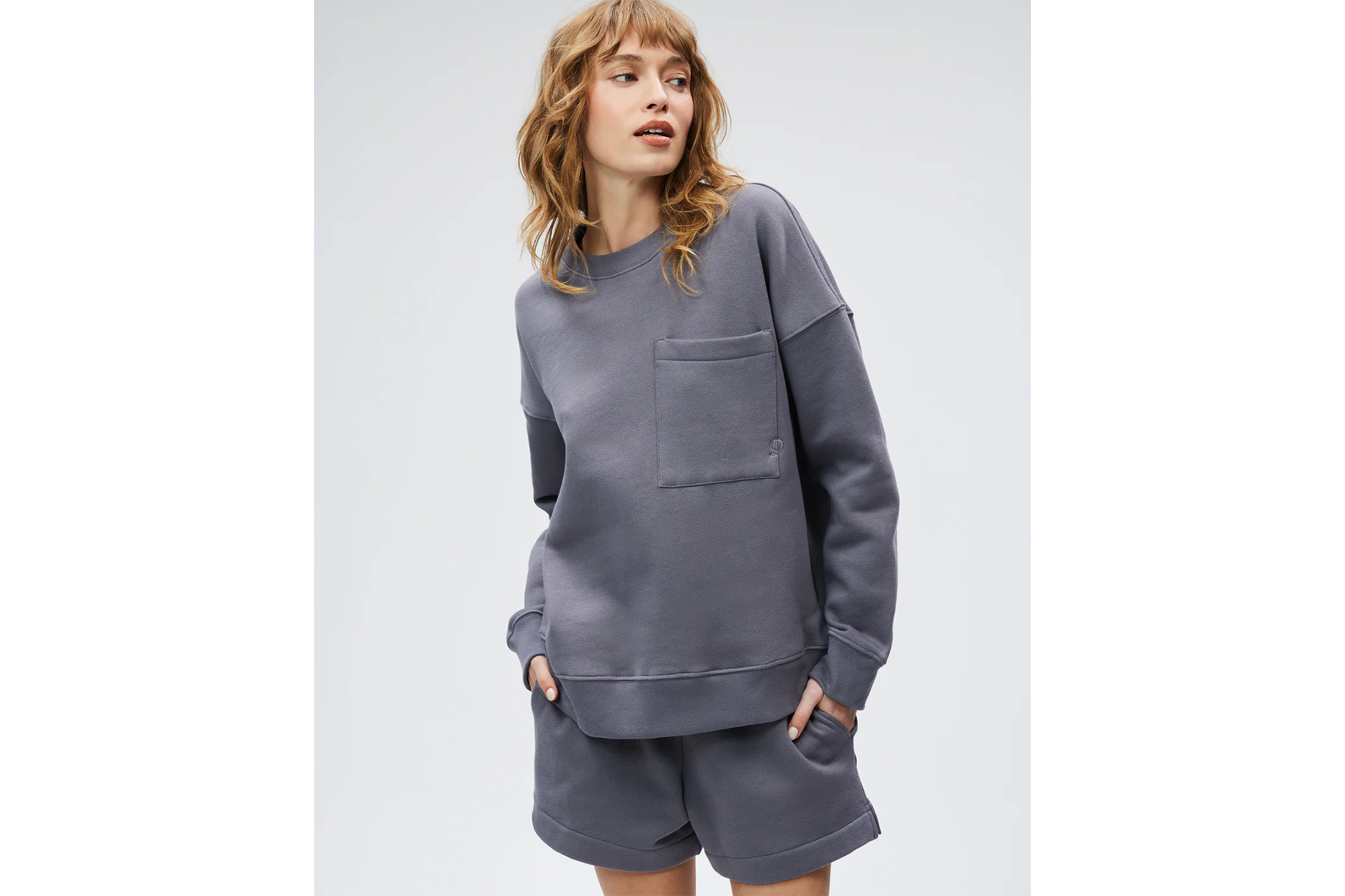 Woman wearing a charcoal grey sweatshirt and matching shorts.