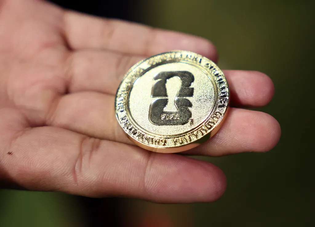 A hand holding a gold coin for the FIFA World Cup 2026.