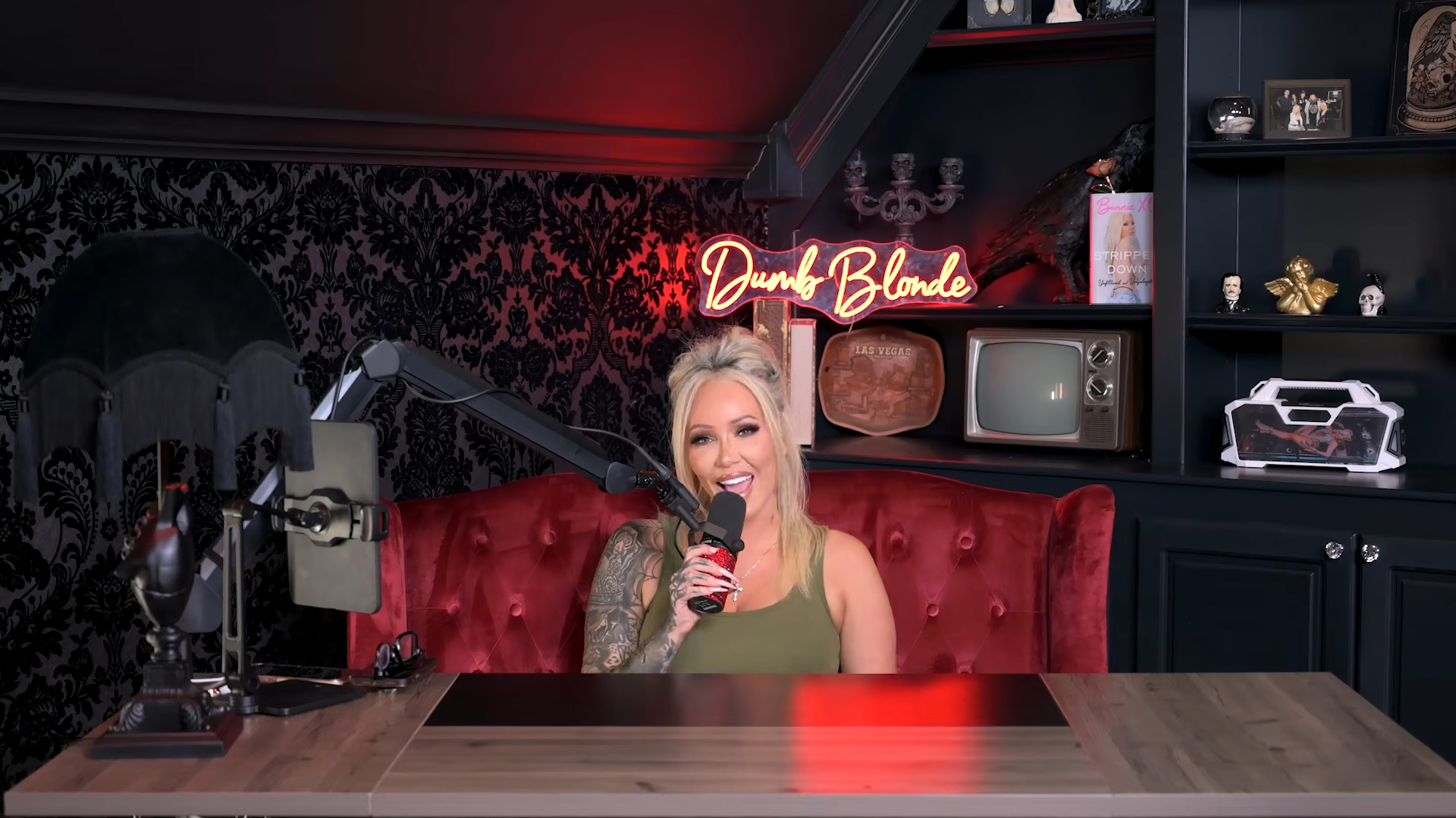 Bunnie XO speaking into a microphone on her "Dumb Blonde Podcast" set.