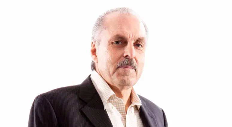 Photo of a man with gray hair and mustache, wearing a suit jacket and collared shirt.