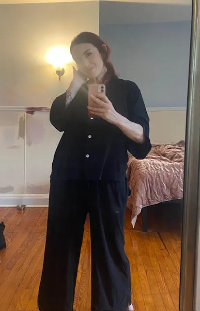 A woman in a black outfit taking a mirror selfie.