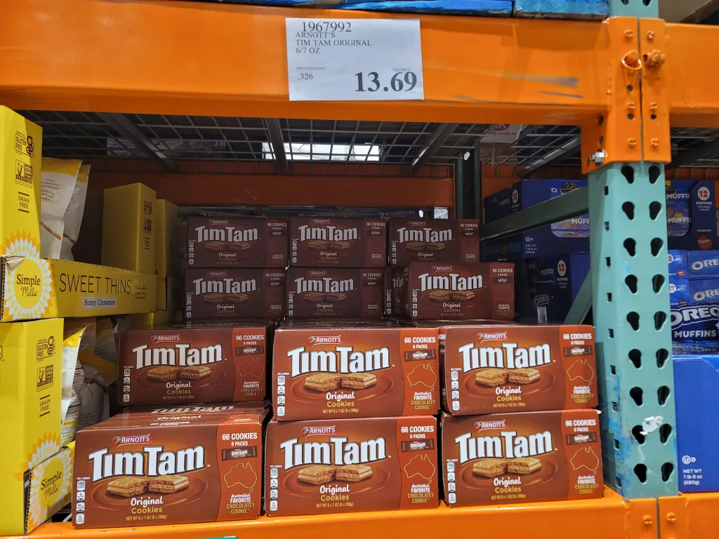 Boxes of Arnott's Tim Tam Original cookies are stocked on a Costco shelf, with a price tag of $13.69 visible.