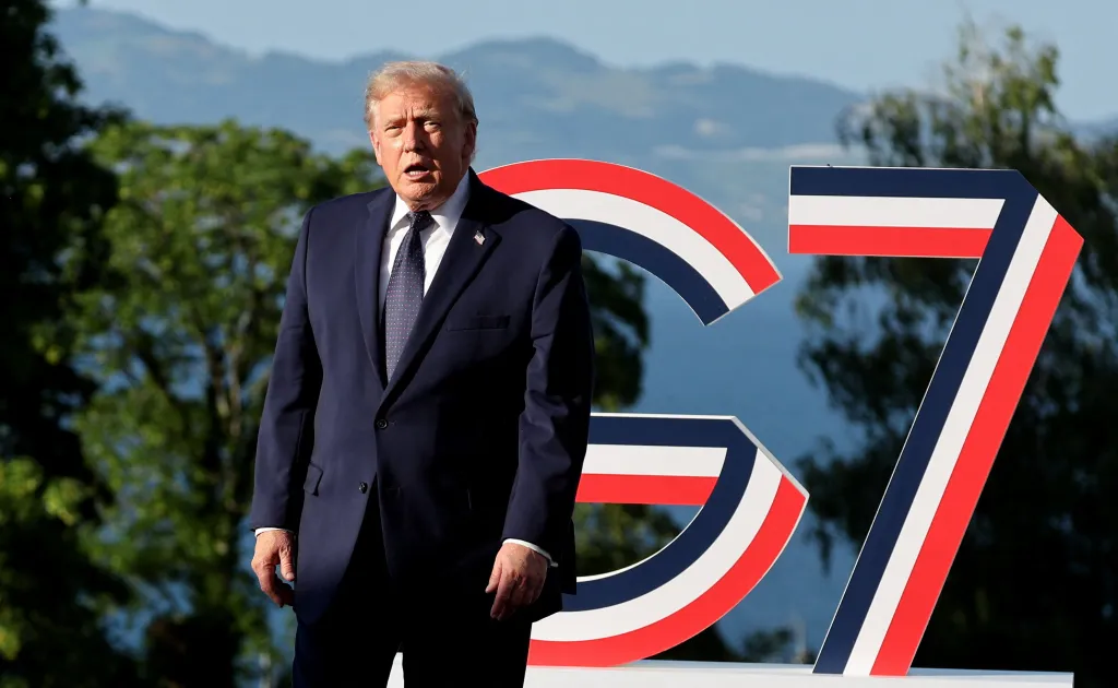Donald Trump standing in front of a G7 sign.