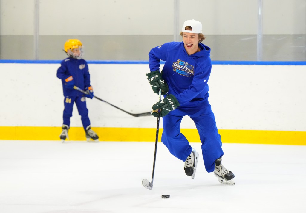 Gavin McKenna practices hockey with a child.