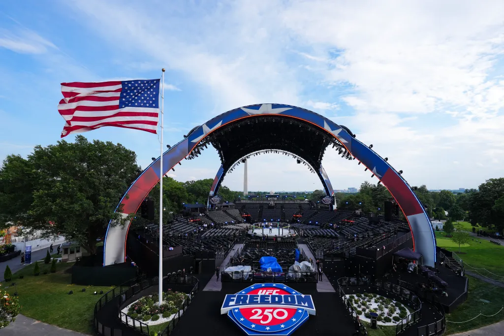 UFC Freedom 250 event setup, with the Octagon in the center, a large American flag waving, and the Washington Monument in the distance.