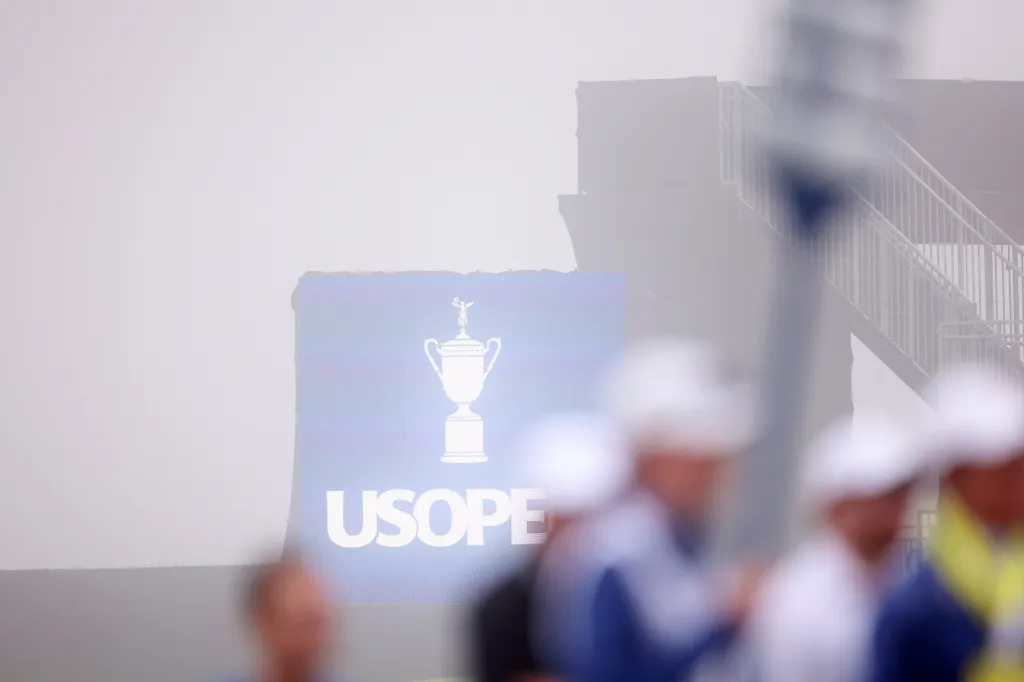 A U.S. Open logo with a trophy icon on a foggy day.