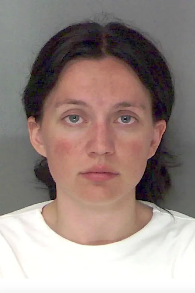Mugshot of a woman with dark hair and a white shirt.