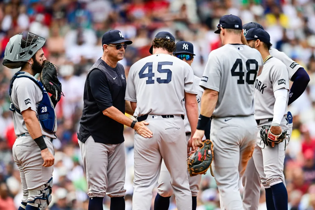 New York Yankees manager Aaron Boone talks with pitcher Gerrit Cole (#45) and other players on the mound during a game against the Boston Red Sox.
