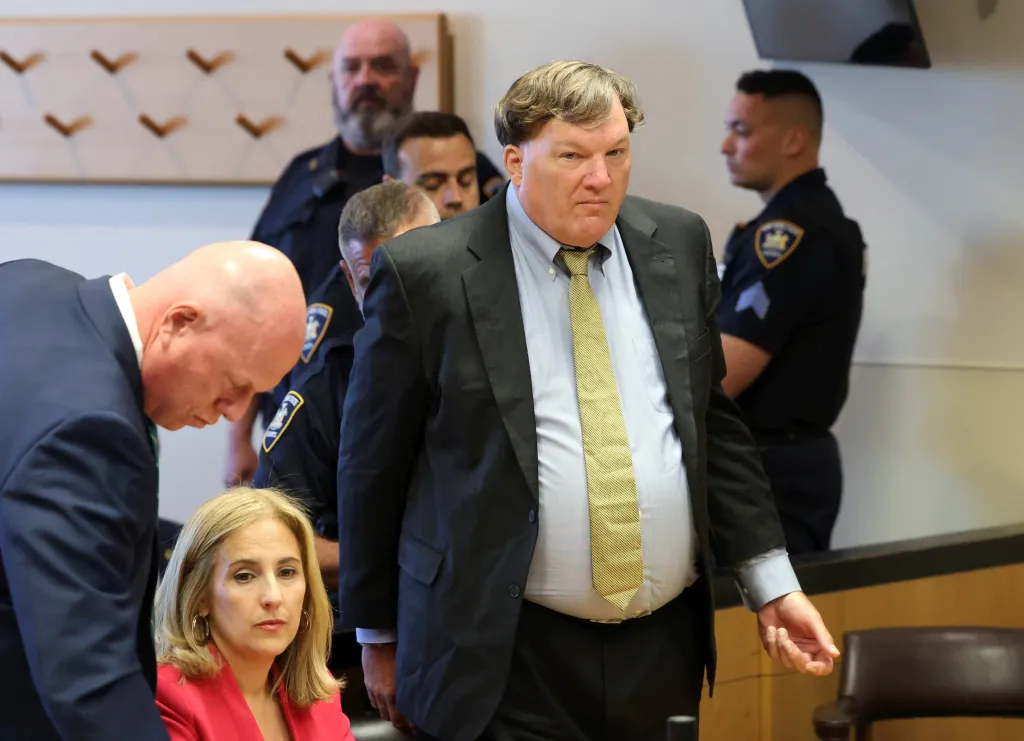 Rex Heuermann in court, flanked by police officers and other individuals.