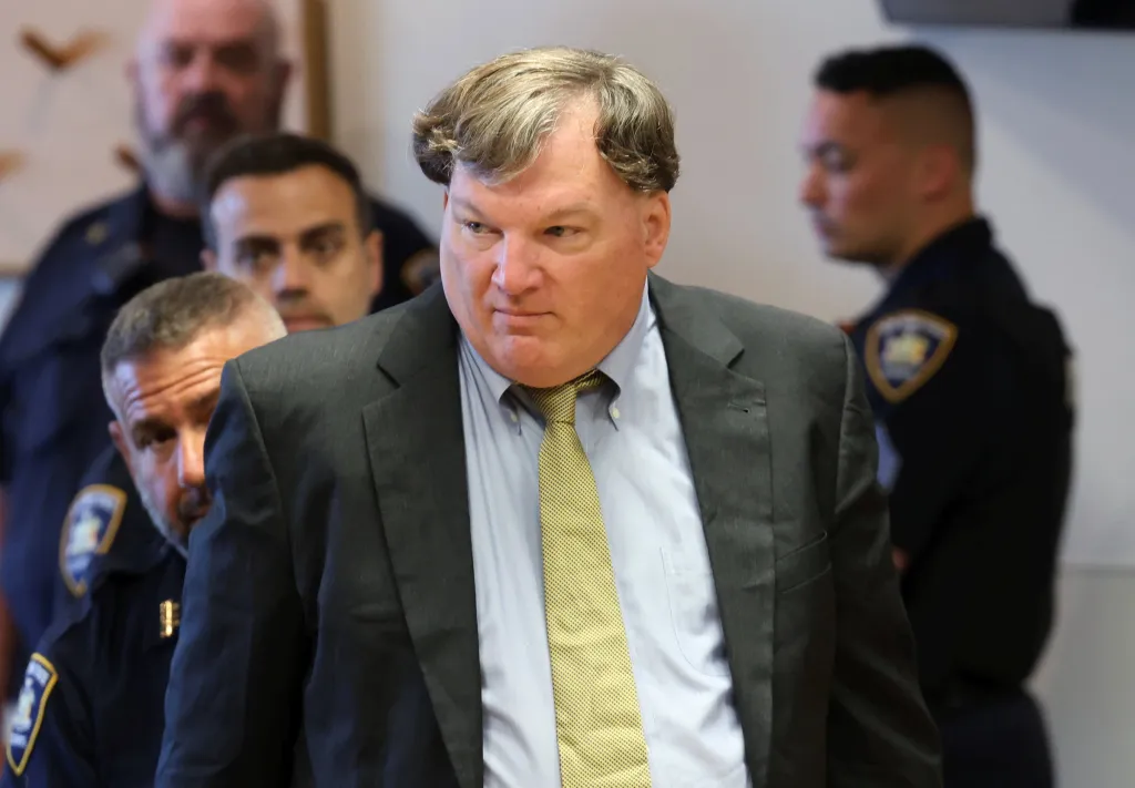 Rex Heuermann walking through a courthouse with officers nearby.